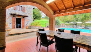 Un espacio al aire libre cubierto con piscina, paredes de piedra y mobiliario exterior.