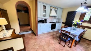 Una cucina compatta con mobili azzurri, un tavolo da pranzo con sedie e una piccola lampada da tavolo.