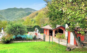 A courtyard with a building, a tree, and a mountain in the background. - Tuscan Hideaway, Private Infinity Pool, Great Outdoor Kitchen & Mountain Views! (Camporgiano)