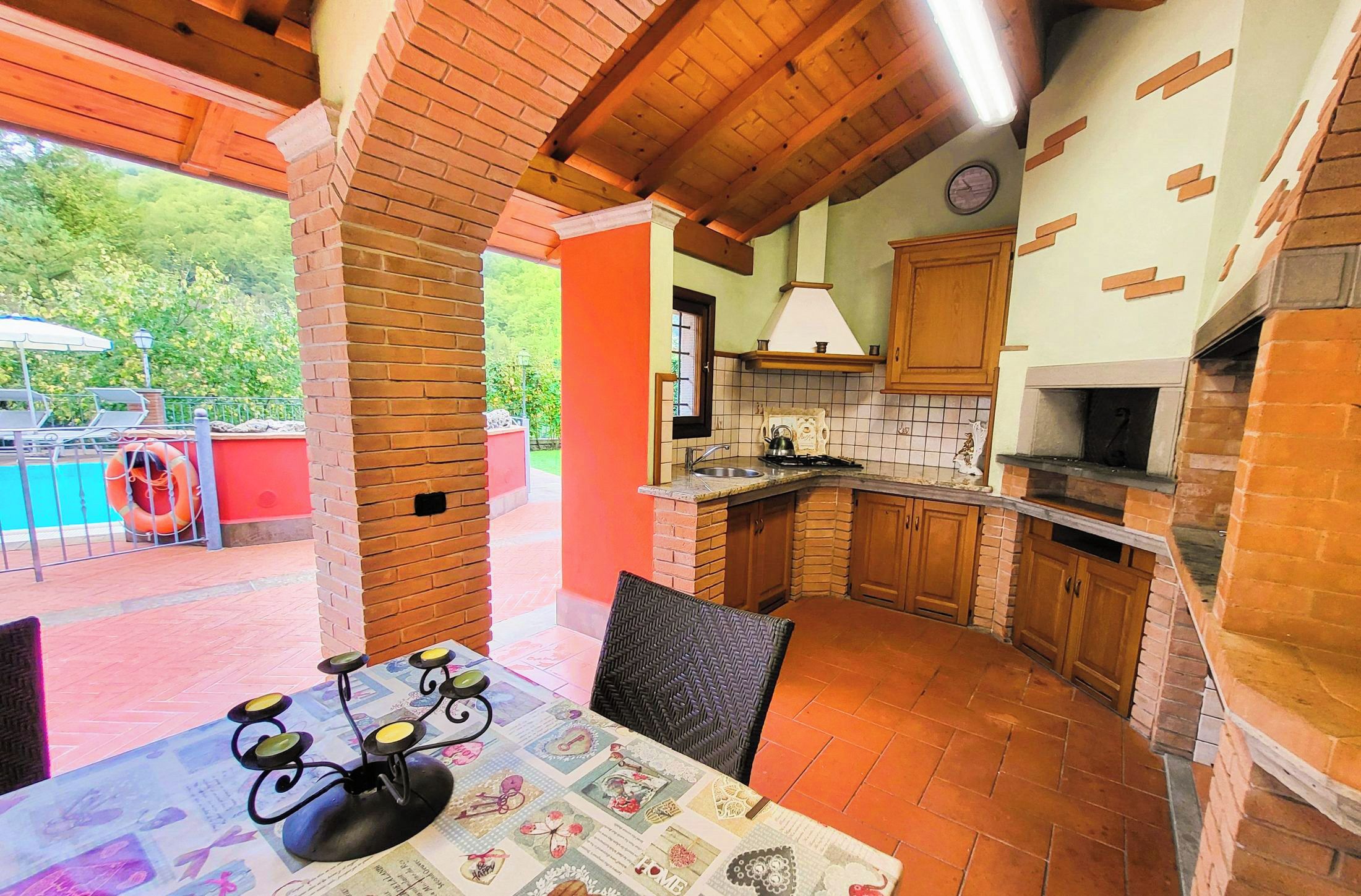 A kitchen with a brick fireplace, wooden cabinets, and a tiled backsplash.