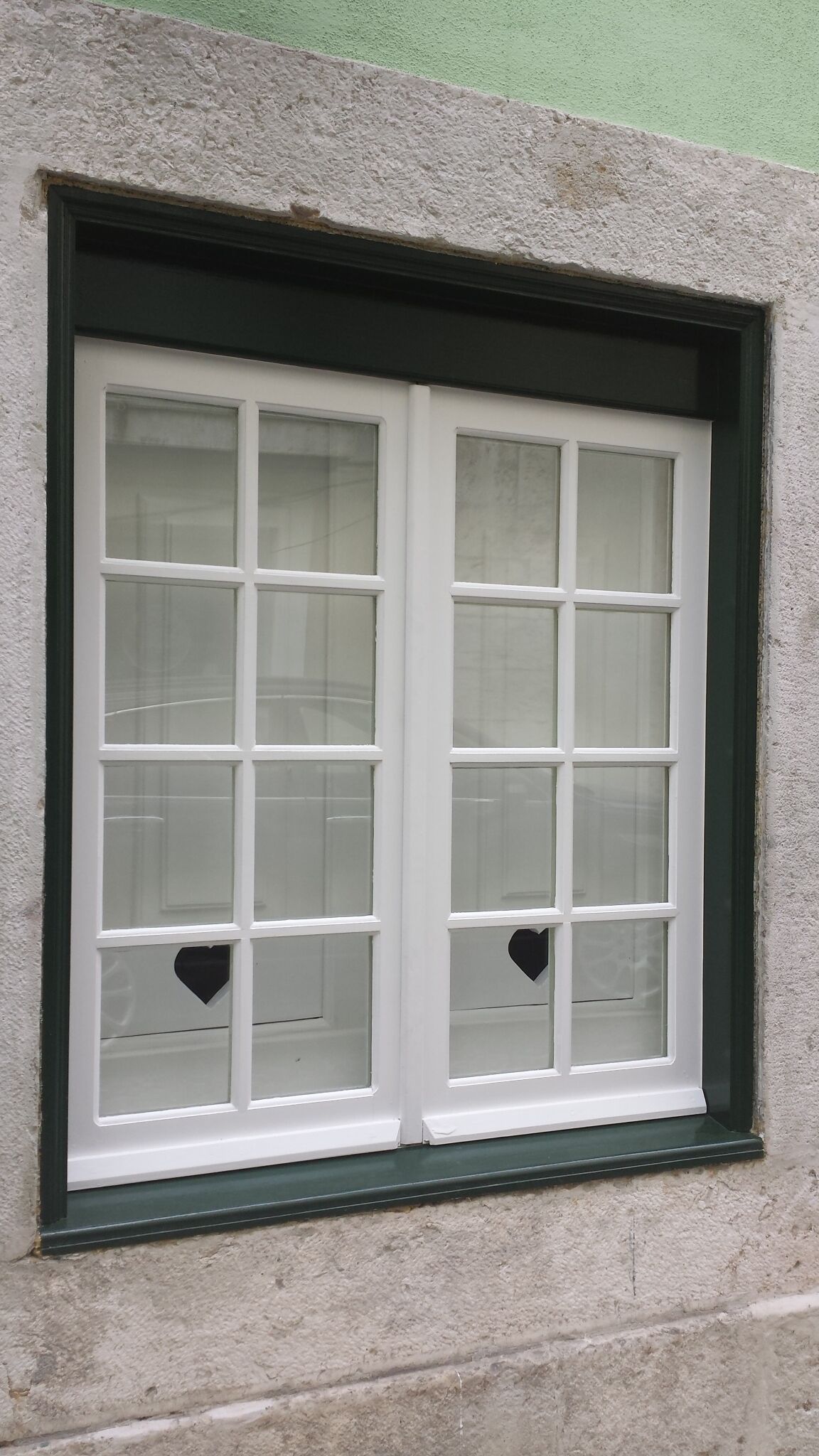 Una ventana con marco blanco y múltiples divisiones, en una pared con textura.