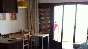 Ein Wohnzimmer mit einer Couch, einem Esstisch und einer Küchenzeile mit einer Arbeitsfläche.