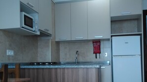 Eine Küche mit Holzausstattung, einer Mikrowelle, einem Spülbecken und einem Kühlschrank.
