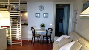 Ein Wohnzimmer mit einer Couch, zwei Sesseln, einem kleinen Tisch und einer Treppe, die in eine obere Ebene führt.