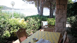 Ein Sitzbereich im Freien mit Tisch und Stühlen, einer Straßenlaterne und Blick auf das Meer.