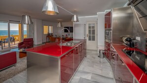 A modern kitchen with red countertops, stainless steel appliances, and pendant lighting.