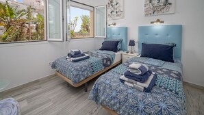 A hotel room with two beds, a large window, and artwork on the walls.