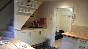 Een kleine keuken met witte kastjes, een houten aanrecht en een klein spoelbakje.