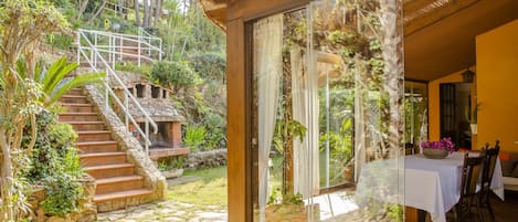 A stone staircase leading to a wooden deck with a glass door leading to a dining area with a table set for two.