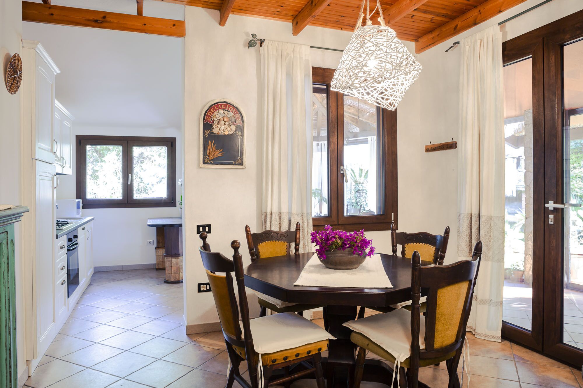 Un coin repas comprenant une table ronde, des chaises, un luminaire suspendu et une fenêtre avec des rideaux.