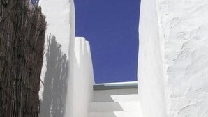A white staircase leading upwards, surrounded by white walls and a clear blue sky.