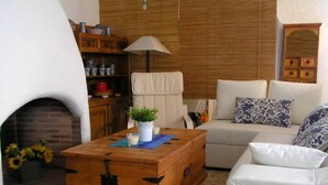 A cozy living room with a fireplace, a wooden chest, a sofa, and a lamp.