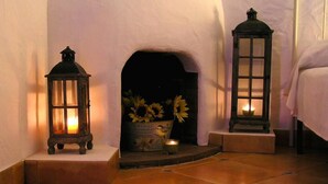 A cozy fireplace area with two lanterns and a flower arrangement.