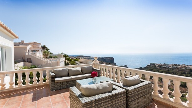A balcony with wicker furniture, a glass coffee table, and a view of the sea and cliffs. - Villa with pool and panoramic views of the Mediterranean Sea (Benitachell)