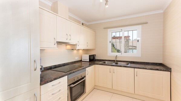 A modern kitchen with white cabinets, a built-in oven, a microwave, and a window with a view of the outside. - Villa with pool and panoramic views of the Mediterranean Sea (Benitachell)