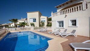 A swimming pool with lounge chairs and a clear blue sky. - Villa with pool and panoramic views of the Mediterranean Sea (Benitachell)