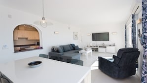 A modern living space with a kitchen, a grey sofa, a white dining table, and a black armchair. - Villa with pool and panoramic views of the Mediterranean Sea (Benitachell)