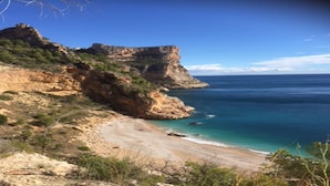 A coastal landscape with a rocky cliff, a sandy beach, and clear blue sea. - Villa with pool and panoramic views of the Mediterranean Sea (Benitachell)
