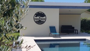 Ein Poolbereich mit Liegestuhl, Sofa und einer Wand mit einem Logo.