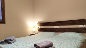 A neatly made bed with a patterned bedspread, a wooden headboard, and two bedside lamps.
