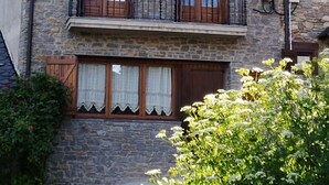 A stone building with two windows and a balcony.