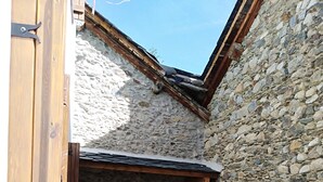 A stone-walled courtyard with a fireplace, a wooden door, and a tiled floor.