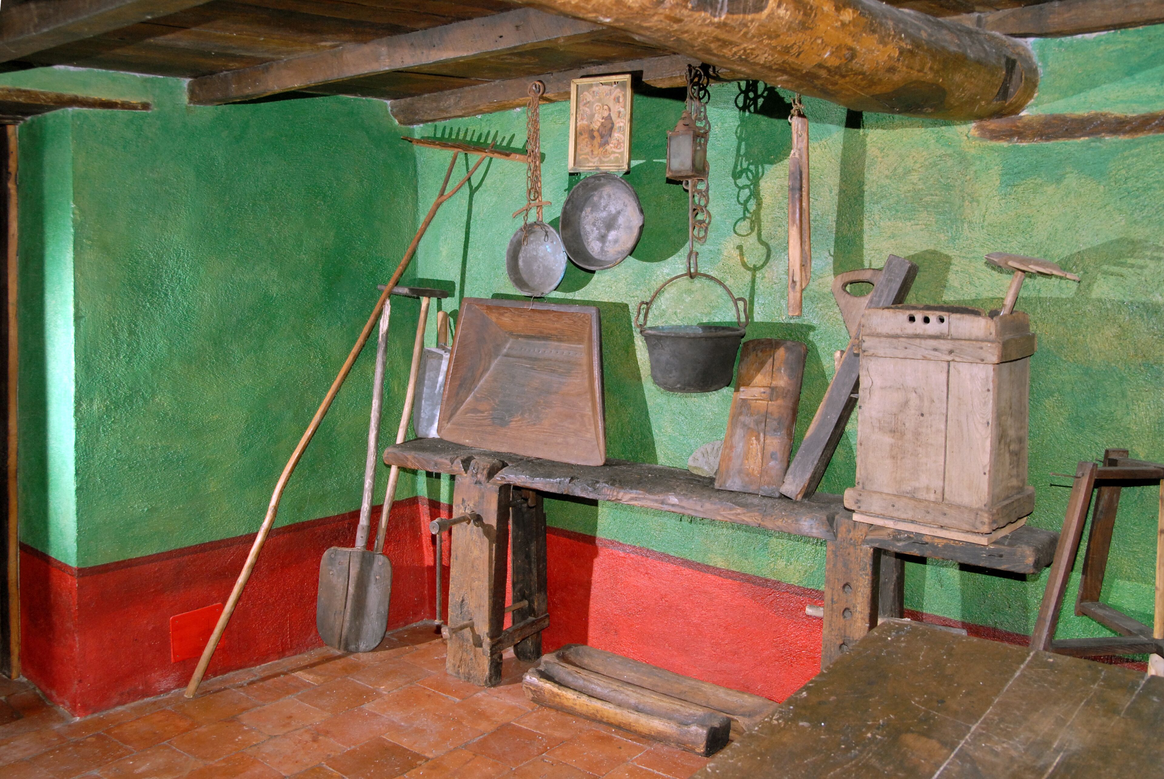 Une cuisine rustique avec des ustensiles en bois, une grande marmite et une lanterne suspendue.