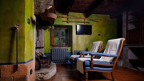 A rustic room with a wooden chair, a window, a radiator, and a television on the wall. - Ancient mill in the "green hearth" of Tuscany (Pieve Fosciana)
