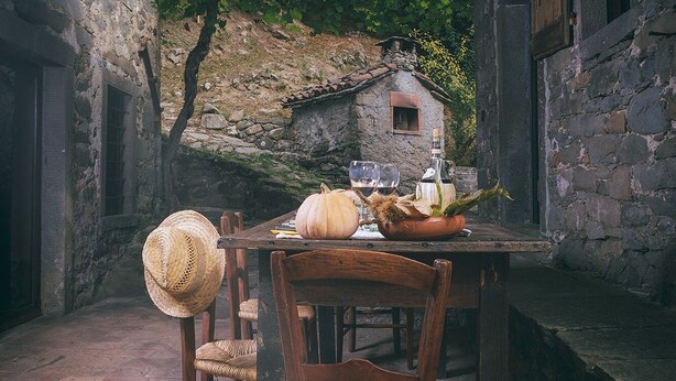 A rustic outdoor dining area with a stone wall, wooden table, and chairs. - Ancient mill in the "green hearth" of Tuscany (Pieve Fosciana)