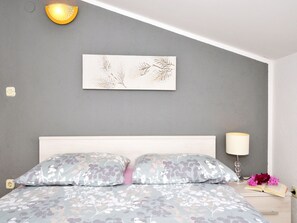 A bedroom with a bed, a bedside lamp, a wall-mounted light fixture, and a floral artwork on the wall. - Seaview Apts, 80 meters to beach, crystal clear sea, 2 apts, large terraces, BBQ (Rogoznica)