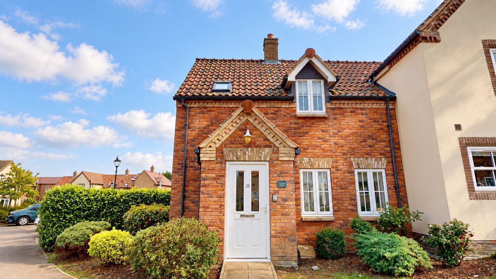 A two-story brick house with a white door, a small window, and a chimney.