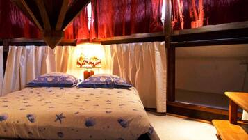 A cozy bedroom with a bed, curtains, a nightstand, and a wooden bench.