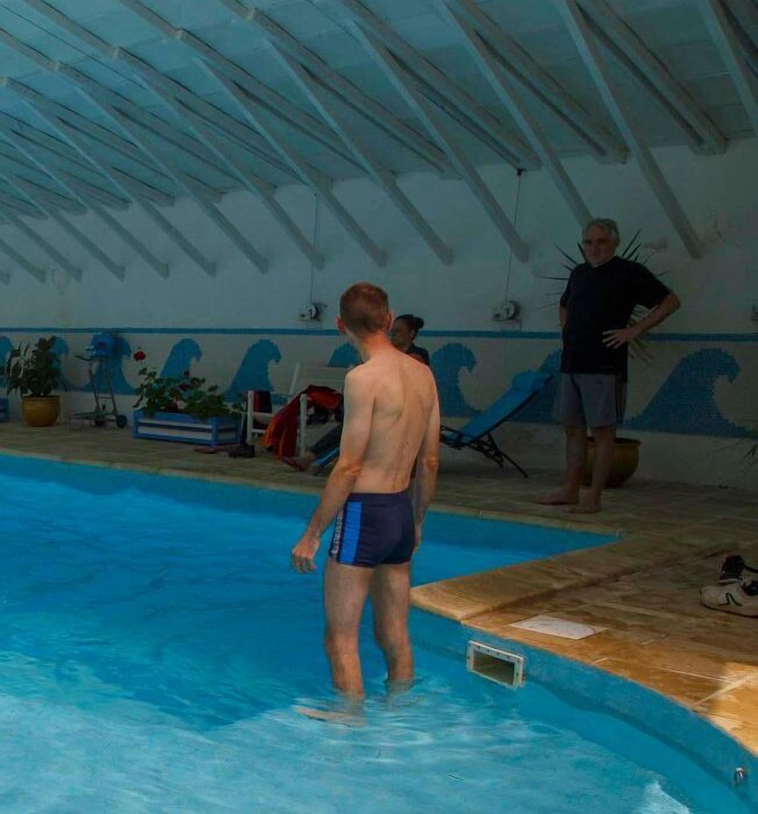 An indoor swimming pool with a tiled floor and a ceiling with a peaked design.