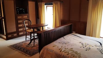 A bedroom with a bed, a wooden chair, a small table, and a radiator.