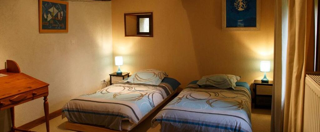 Un dormitorio con dos camas, un escritorio de madera y una mesita.