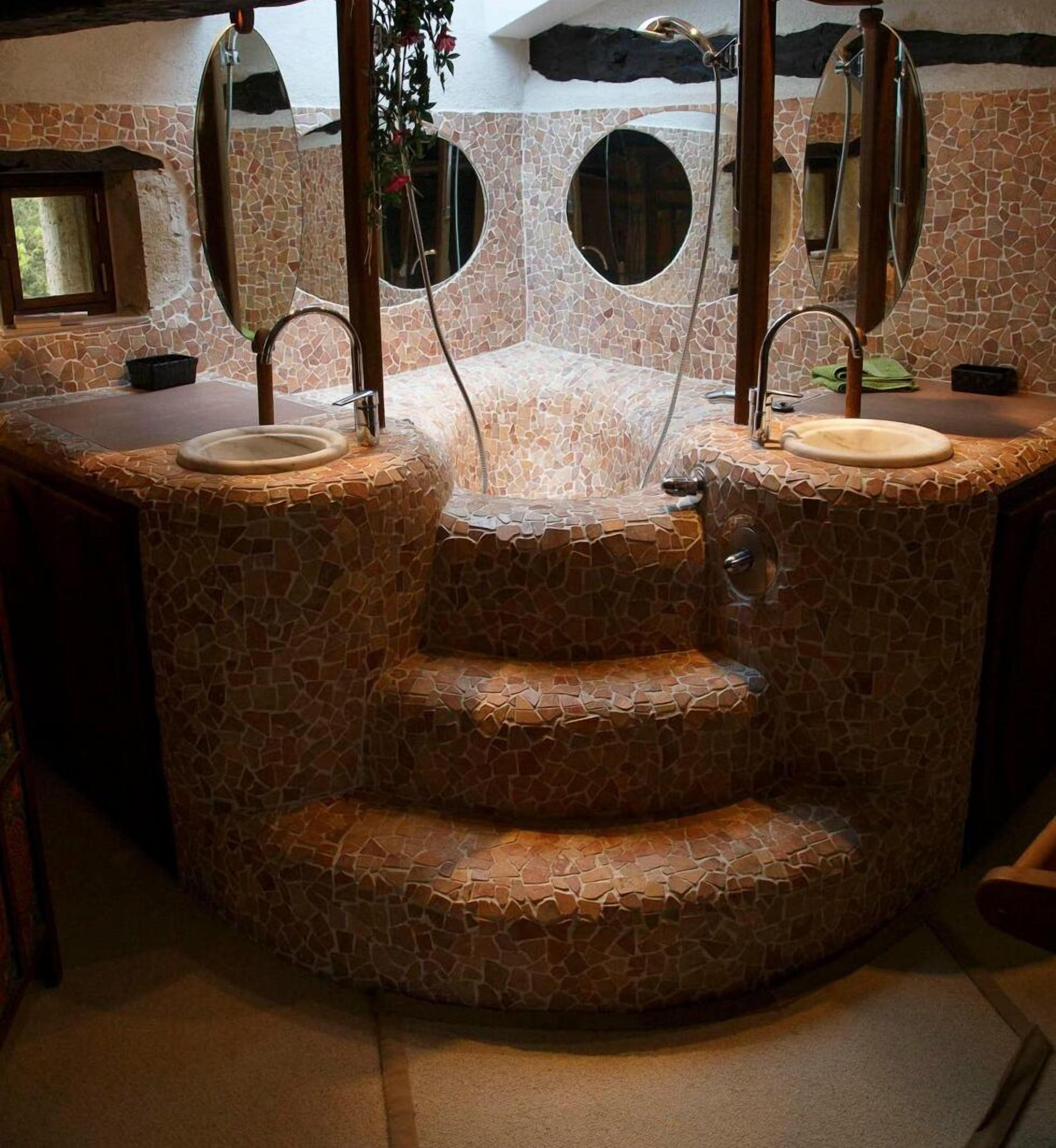 A bathroom with a stone mosaic design, two sinks, and a mirror above each sink.