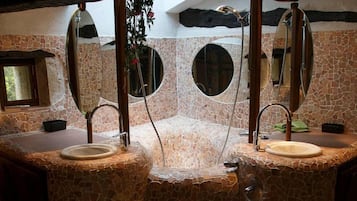 A bathroom with a stone mosaic design, two sinks, and a mirror above each sink.
