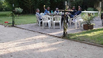 An outdoor patio with a dining table and chairs, a barbecue grill, and a croquet field.