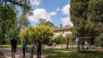 Un parc avec un kiosque, des tables de pique-nique et un bâtiment en pierre en arrière-plan.