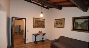 A room with a wooden floor, a brown sofa, a table with a decorative item, and three framed paintings on the wall. - Holiday home in the Florentine Chianti area (Reggello)