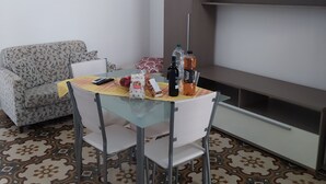 Un espacio habitable compacto con una mesa de comedor, sillas, un sofá, una cama litera y un suelo estampado.