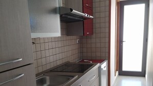 Una cocina con electrodomésticos de acero inoxidable, gabinetes rojos y salpicadero de azulejos.