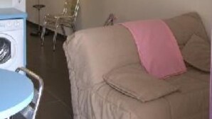 A room with a bed, a chair, a small table, and a lamp.