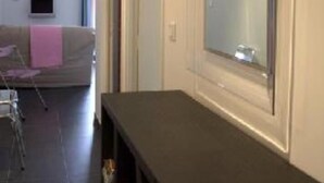 A modern living room with a large window, a sofa, and a flat-screen TV on a stand.
