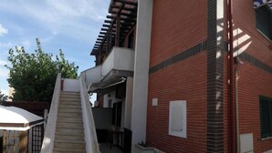 Un edificio de varios pisos con fachada de ladrillo, una escalera que conduce a un nivel superior y un espacio al aire libre techado.