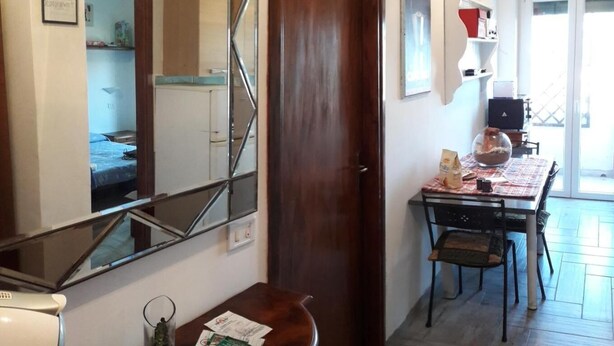 Una habitación de hotel con una puerta de madera, una mesa pequeña con una silla, un espejo y una ventana.