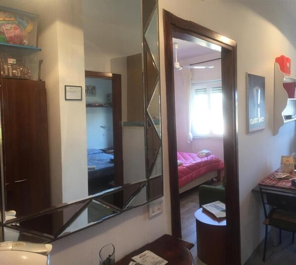 A compact room with a bed, a desk, a chair, and a mirror.