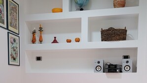 A compact living space with a bed, a small table with food, shelves with decorative items, and a globe. - APARTMENT IN THE HISTORICAL CENTER OF CATANIA (CATANIA)