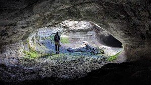 A person standing in a cave with a natural pool of water and a small mound of rocks. - APARTMENT IN THE HISTORICAL CENTER OF CATANIA (CATANIA)
