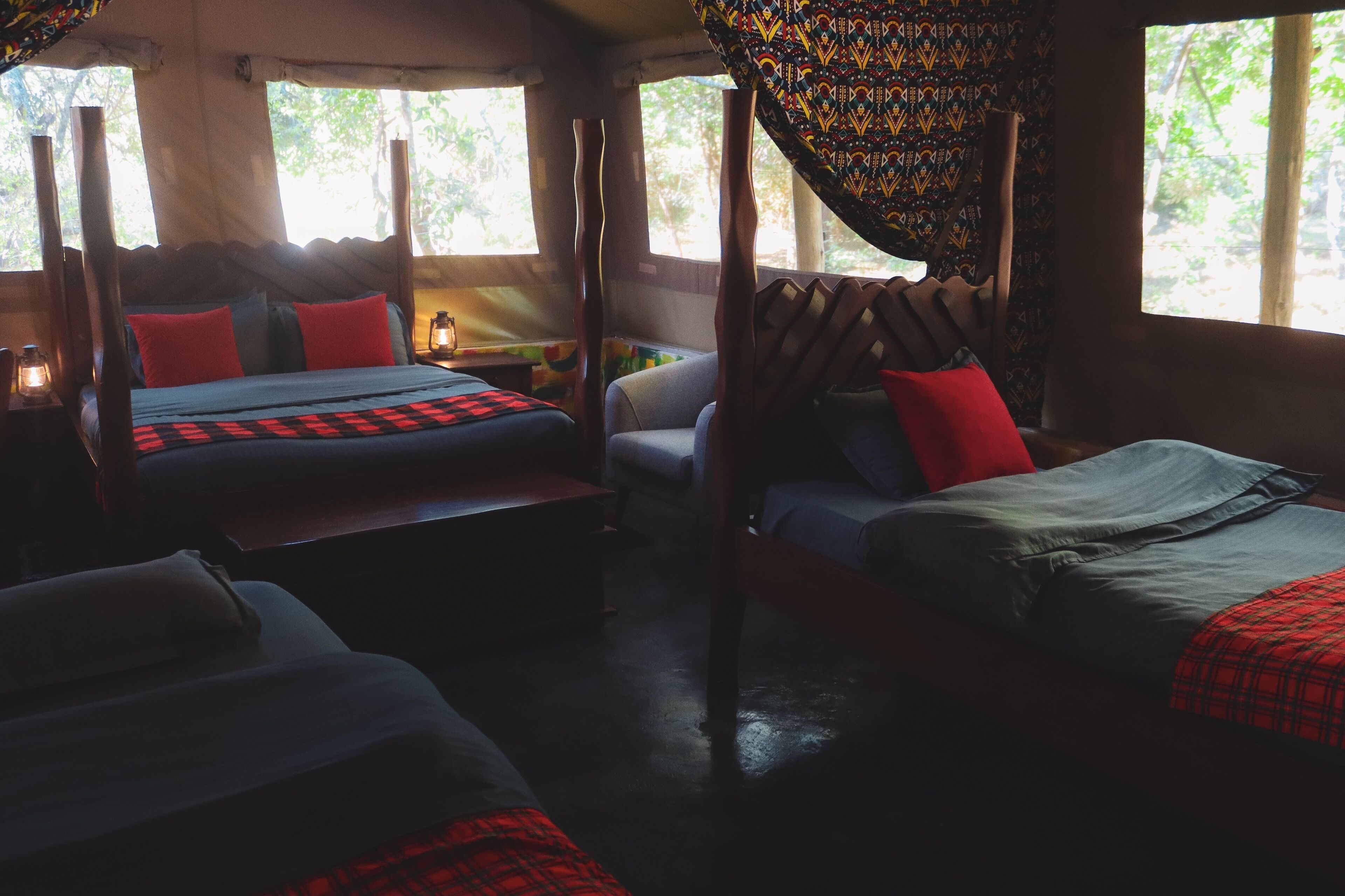 A room with two beds, each with a canopy, and a small table with a lamp.